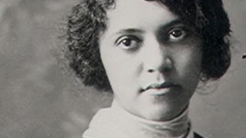 Old black and white photo of a young black woman wearing a graduation cap and gown.