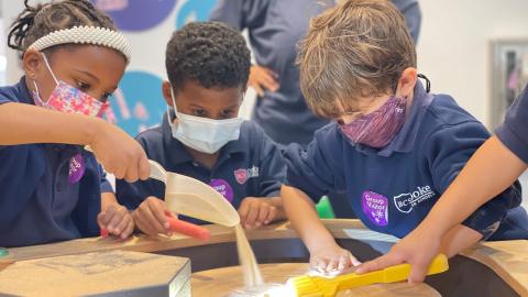 three children explore a sand exhibit