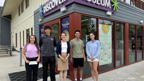 five people stand in front of a museum building