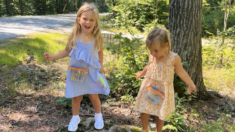 two young girls stand on a large rock