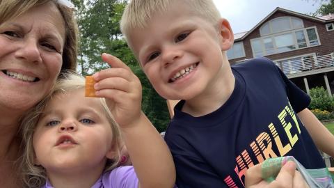 a grandmom smiles with her two grandchildren