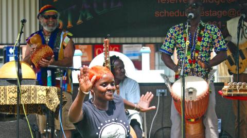 A woman dances in front of a stage where musicians are playing percussion instruments