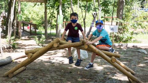 two boys sit on a small bridge exhibit