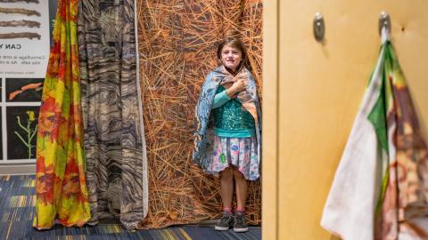 a child pretends to be camouflaged against a patterned backdrop 