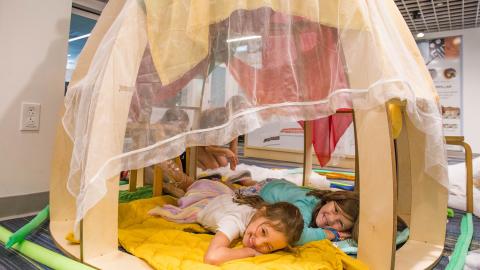 two children lay in a pretend caterpillar nest