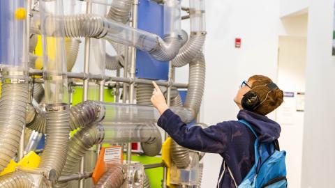 a boy wearing noise-reducing headphones explores an air exhibit