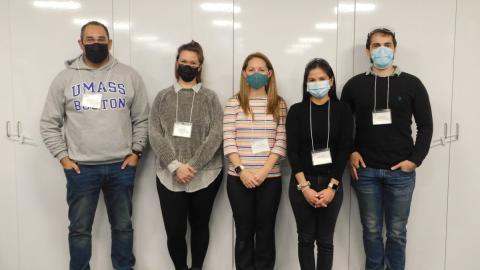 five adults wearing face masks and nametags stand together