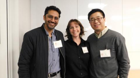 Three adults wearing nametags stand together, smiling