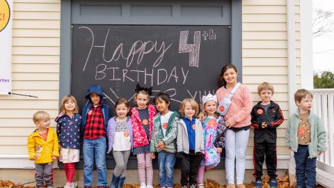 a group of children stand lined up in front of a building