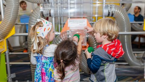 three young children play at a museum exhibit