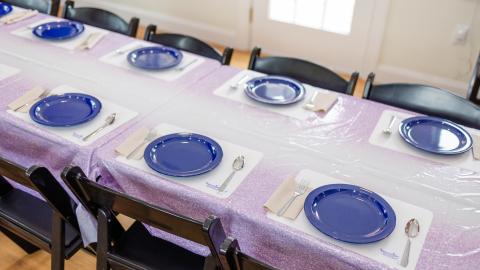 a table set with blue plates, no people sitting in the chairs