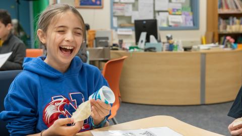 a girl laughs while performing a science experiment