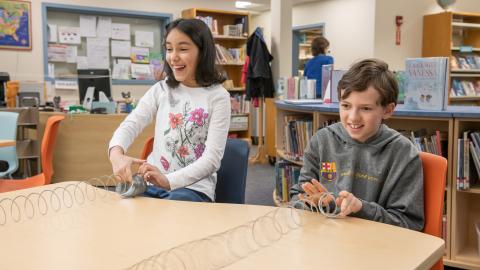 two students use Slinky(R) toys to explore sound vibrations