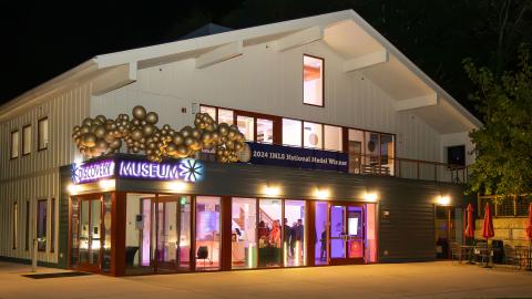 a nighttime photo of a museum building with balloon decorations and event lighting