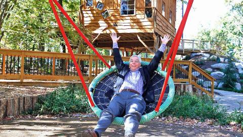 enthusiastic man laying in nest swing, arms and legs akimbo