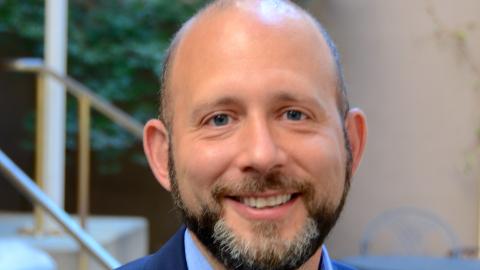 bald man with blue eyes looking at camera