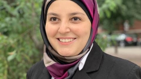 a photo of a woman wearing a dark jacket and colorful head scarf