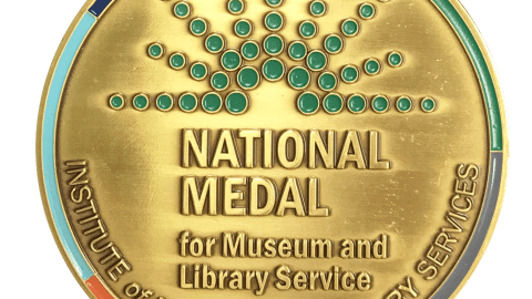 a round gold medallion that says, "National Medal for Museum and Library Service"