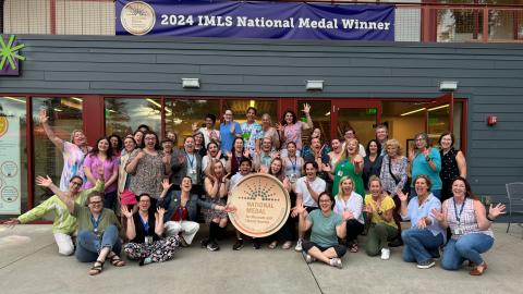 a big group of people pose for a photo, holding their arms out excitedly