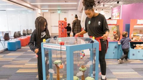 a teen and younger child explore an exhibit that involves cooperation