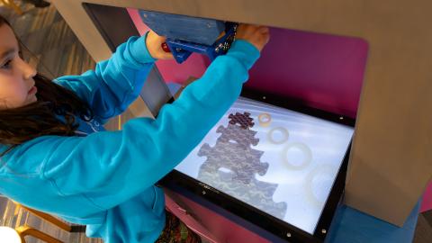 a child uses a suspended camera over a light table