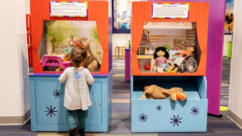 a young girl stands in front of an exhibit about storytelling