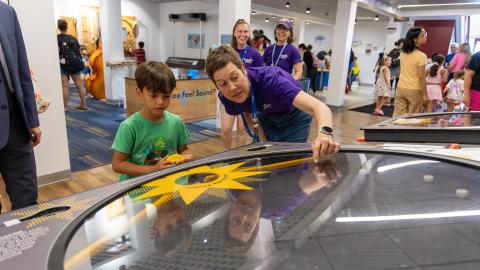 an adult and child use a pinball-like exhibit about solar cell technology
