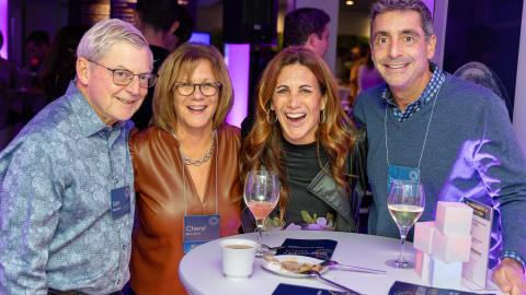 four smiling and laughing people pose for a photo at a party