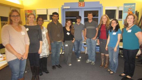 Ten adults wearing nametags stand together, smiling