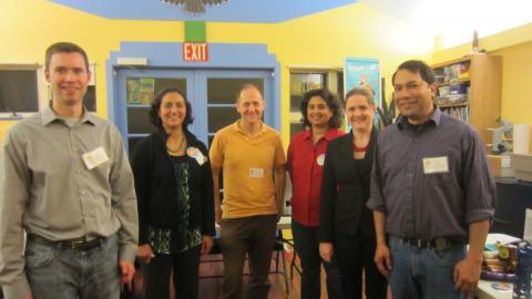 Six adults wearing nametags stand together, smiling