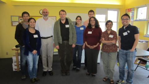 Nine adults wearing nametags stand together, smiling