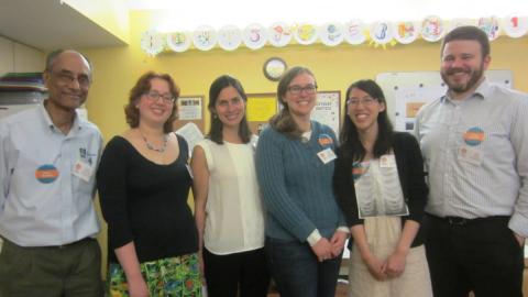 Six adults wearing nametags stand together, smiling