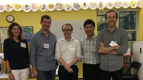 Five adults wearing nametags stand together, smiling