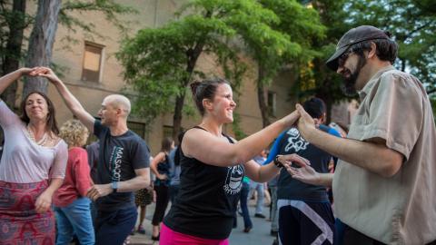 Several people are dancing outdoors in the daytime
