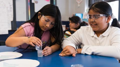 two girls conduct a chemistry experiment in school