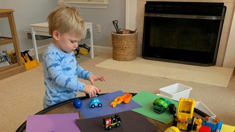 a young boy plays with cars on a low table