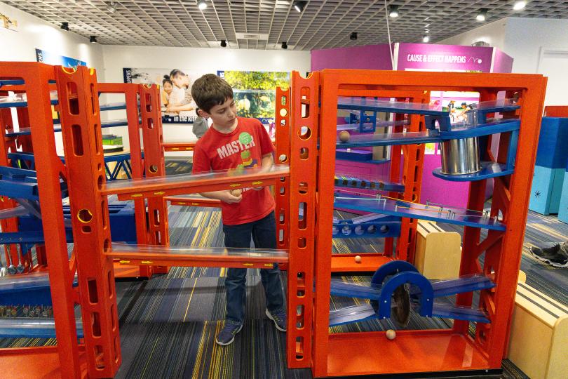 a boy explores an exhibit of balls and ramps