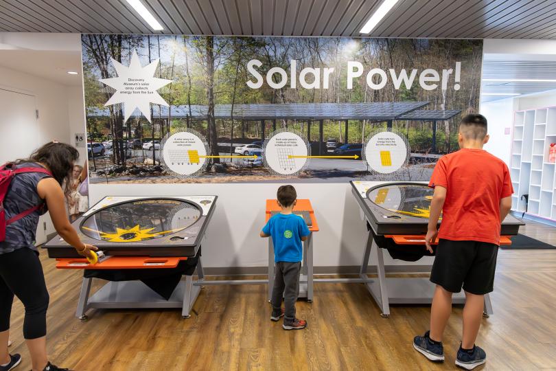 3 people play at an exhibit about solar cell technology