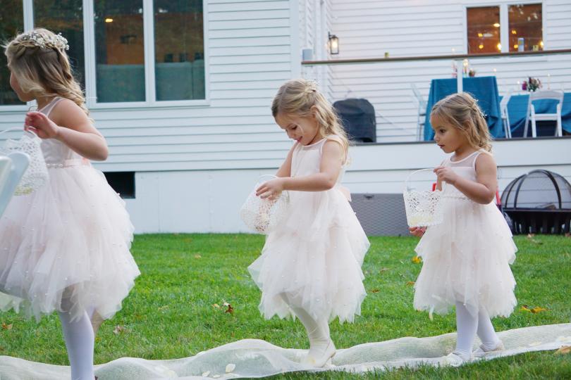 three small girls in dresses in a back yard