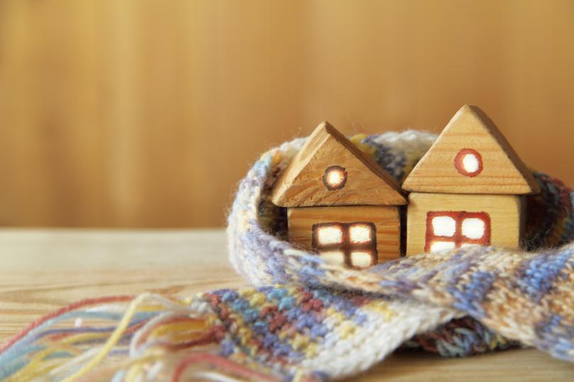 two small toy wooden houses sit on a table with a knitted scarf wrapped around them