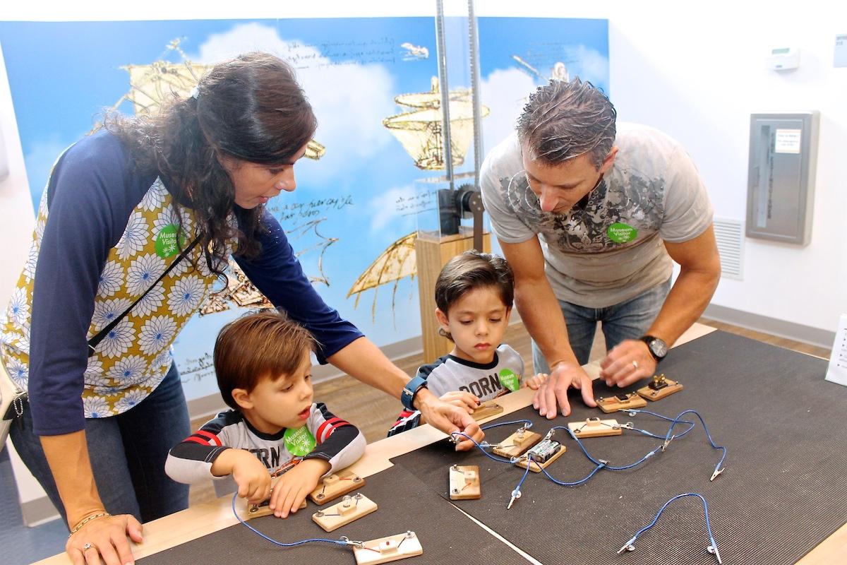 A family plays together at a table of circuit toys.