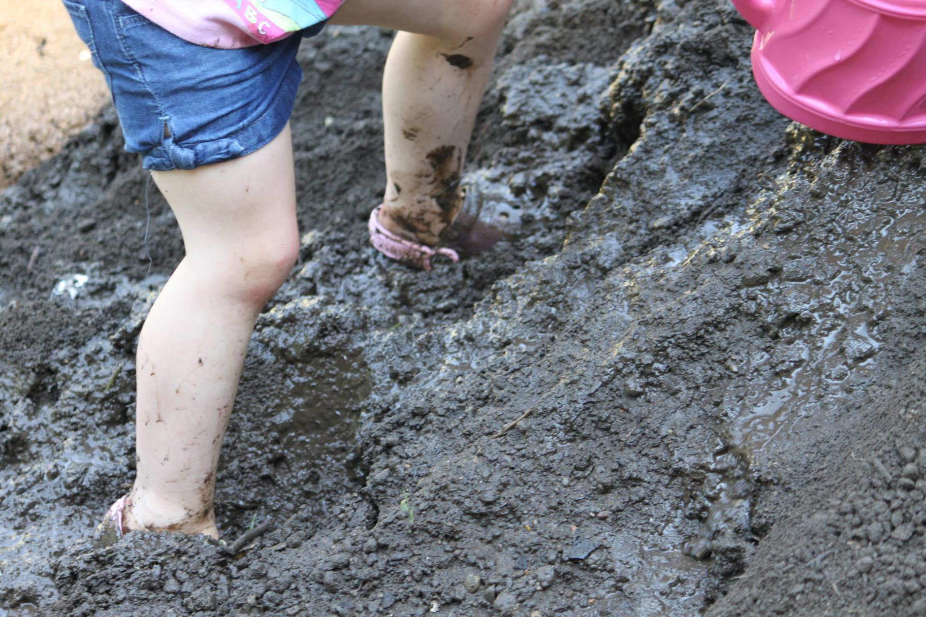 a child sinks in mud while climbing a mud hill