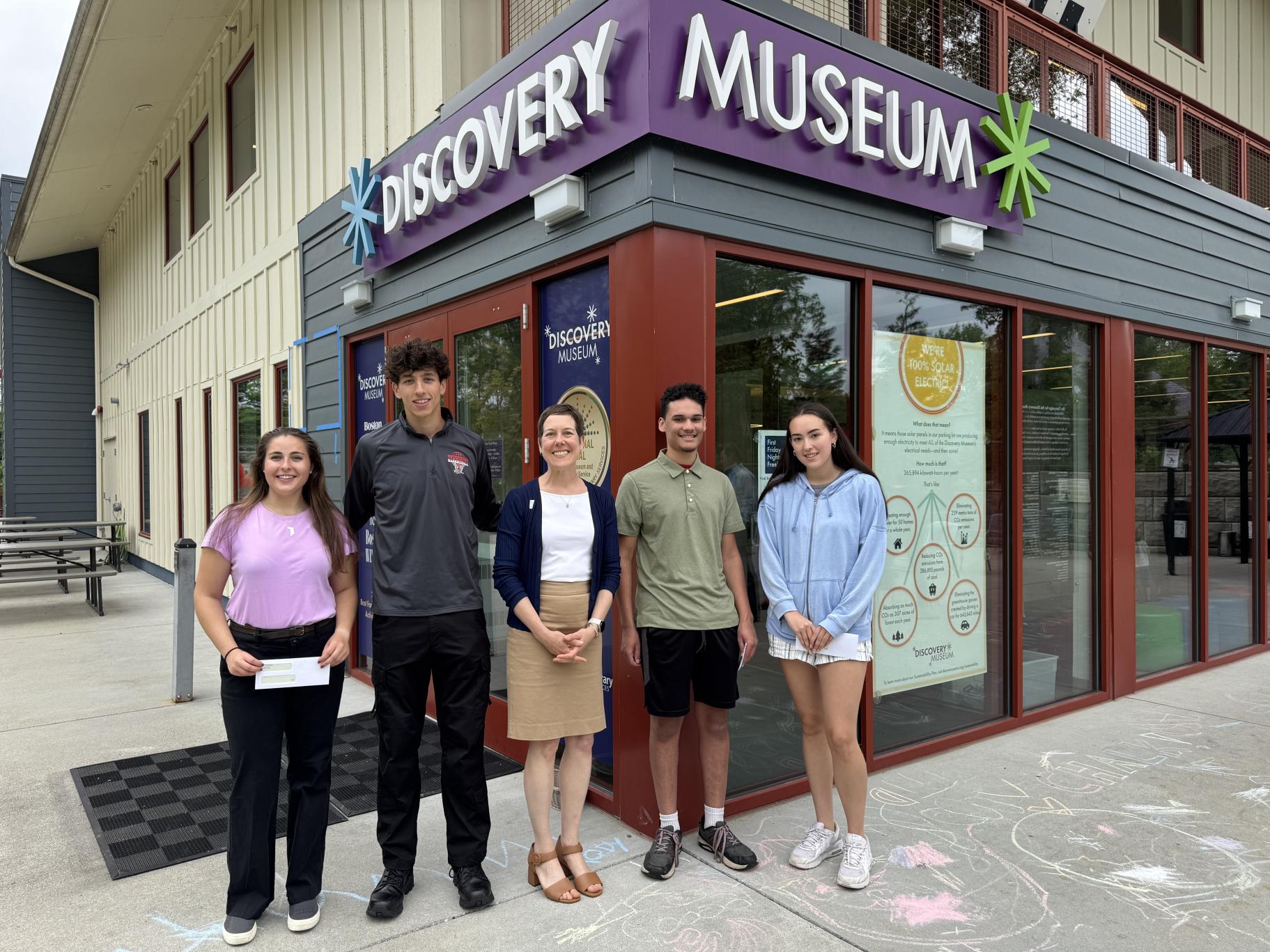 five people stand in front of a museum building