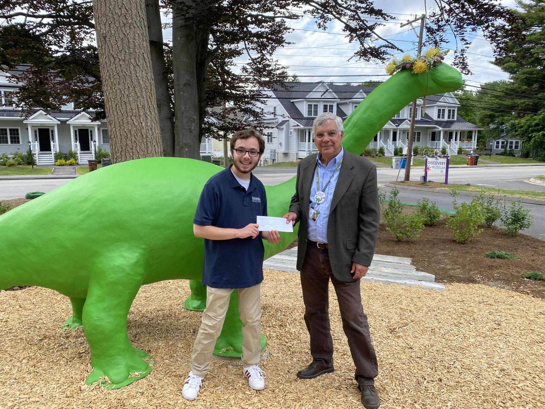 CEO Neil Gordon and scholarshp recipient Ajax Benander at Discovery Museum with Bessie the Dinosaur